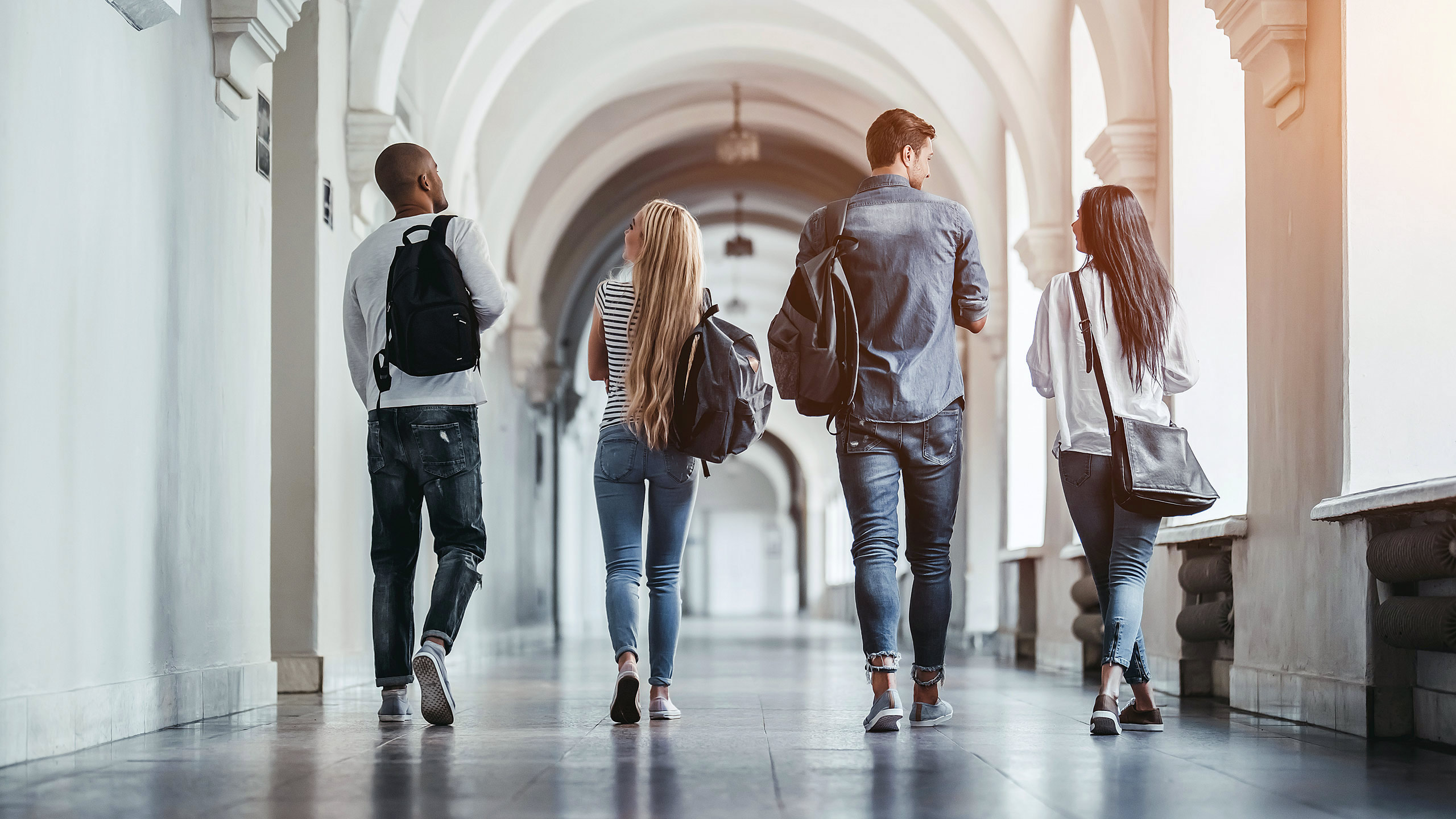 four integrated manufacturing students walking down the hall of a large academic building